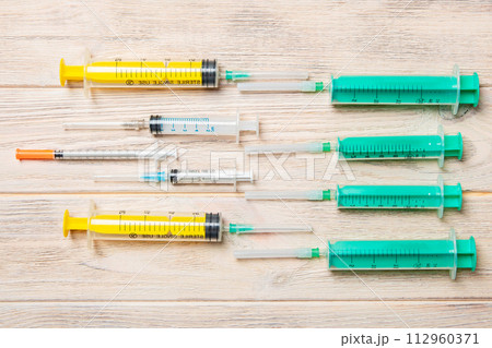 Top view of many syringes and one insulin syringe prepared for injection at wooden background. Treatment concept with copy space 112960371