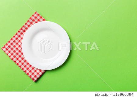 Top view on colored background empty round white plate on tablecloth for food. Empty dish on napkin with space for your design 112960394