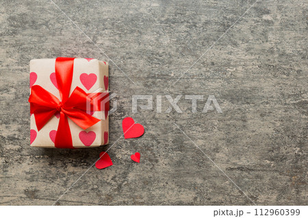 Top view photo of valentine day decorations gift box with red ribbon bow on colored background. Holiday gift boxes with top view 112960399
