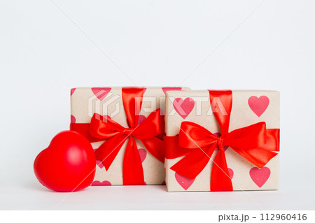 gift box with red bow and red heart on colored background. Perspective view. Flat lay gift box with red bow and red heart on colored background. Perspective view. Flat lay 112960416