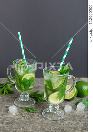 Mojito cocktail. Refreshing mojito cocktail with lime, lemon and mint in a tall glass with a stick Mojito cocktail. Refreshing mojito cocktail with lime, lemon and mint in a tall glass with a stick 112960506