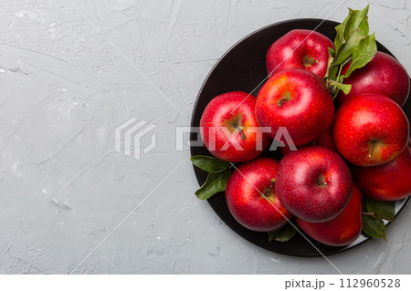 Many red apples on cement background, top view. Autumn pattern with fresh apple above view Many red apples on cement background, top view. Autumn pattern with fresh apple above view 112960528