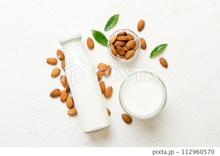 Top view of the almond milk in the glass bottle with almond nuts on the colored table. top view vith copy space 112960570