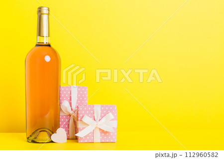 Bottle of wine on colored background for Valentine Day with gift box. Heart shaped with presrnt box perspective view with copy space 112960582
