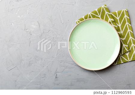 Top view on colored background empty round green plate on tablecloth for food. Empty dish on napkin with space for your design 112960593