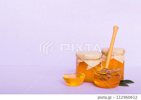 Honey in jar with leaves and honey dipper on colored background top view with copy text Honey in jar with leaves and honey dipper on colored background top view with copy text 112960612