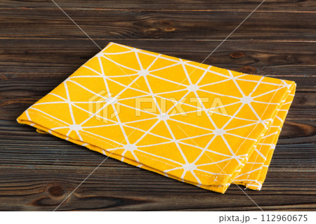 top view with yellow empty kitchen napkin isolated on table background. Folded cloth for mockup with copy space, Flat lay. Minimal style top view with yellow empty kitchen napkin isolated on table background. Folded cloth for mockup with copy space, Flat lay. Minimal style 112960675