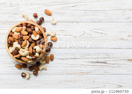 Assortment of nuts in wooden bowl on colored table. Cashew, hazelnuts, walnuts, almonds. Mix of nuts Top view with copy space Assortment of nuts in wooden bowl on colored table. Cashew, hazelnuts, walnuts, almonds. Mix of nuts Top view with copy space 112960730
