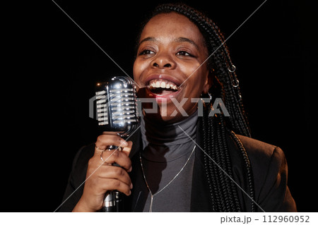 Front view portrait of Black woman singing to microphone performing on stage in theater 112960952
