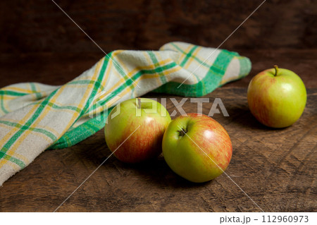 Three green apples on wooden background with green kitchen towel.. Three green apples on wooden background with green kitchen towel.. 112960973