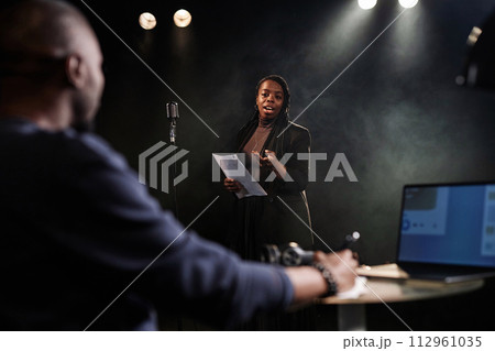 Portrait of Black young woman performing on stage with theater director watching rehearsal or casting process copy space 112961035