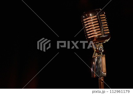 Close up of retro microphone on stage with black background copy space Close up of retro microphone on stage with black background copy space 112961179