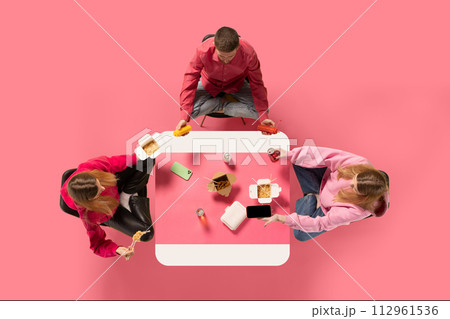 Creative collage. Group of people, friends sitting at Asian cafe and eating delicious food while speaking against pink background. 112961536