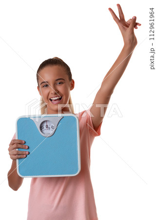 Teenager girl isolated on white background holding the weighing scale and showing victory sign 112961964