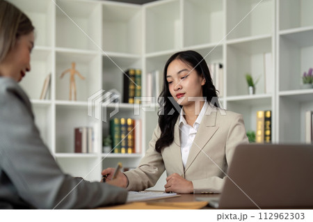 Lawyers woman and businesswoman discussing contract papers sitting at the table. Concepts of law, advice, legal service Lawyers woman and businesswoman discussing contract papers sitting at the table. Concepts of law, advice, legal service 112962303