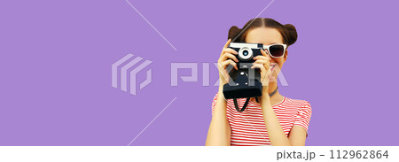 Portrait of happy young woman photographer with film camera, female on violet studio background Portrait of happy young woman photographer with film camera, female on violet studio background 112962864