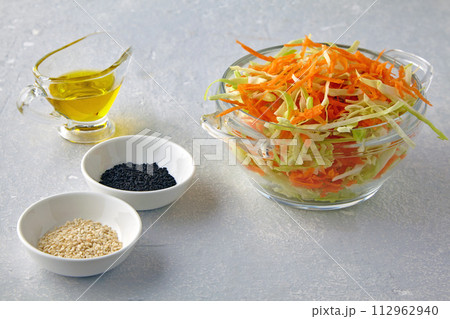 Summer vegetable salad of chopped carrots and cabbage with cumin and sesame seeds with olive oil on a light stone table Summer vegetable salad of chopped carrots and cabbage with cumin and sesame seeds with olive oil on a light stone table 112962940