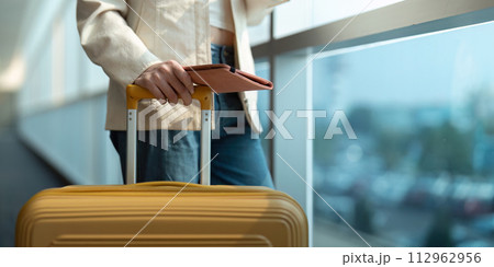Hand of woman passenger holding passport with the flight in airport terminal 112962956