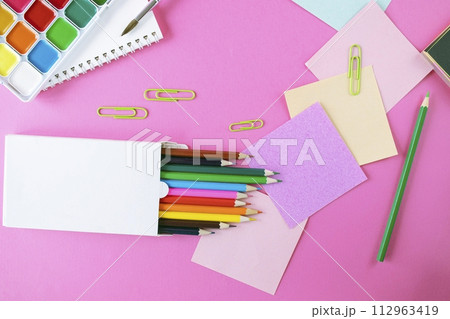 Back to school concept with colored pencils, stickers, alarm clock and notepad on pink background 112963419