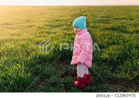 Little girl walking in the field with sunshine in spring Little girl walking in the field with sunshine in spring 112963470