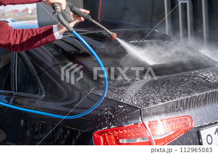 A man washes off the foam while washing the car. A vehicle is engulfed in soapy foam during a car wash, covering the tires, wheels, hood, and entire exterior of the car. Self-service car wash A man washes off the foam while washing the car. A vehicle is engulfed in soapy foam during a car wash, covering the tires, wheels, hood, and entire exterior of the car. Self-service car wash 112965083
