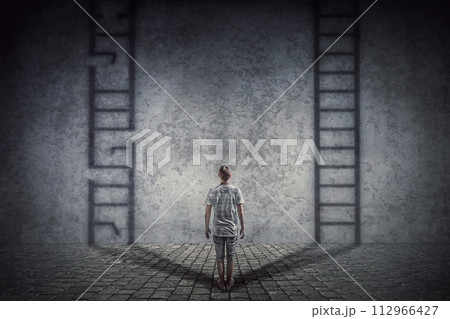 Person stands in front of a wall casting two ladder shadows with one broken on the left and another ready to use on the right. Dilemma and choice concept between good and bad 112966427