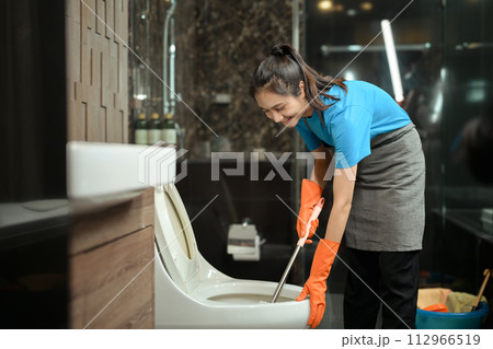 Female cleaner wearing gloves cleaning toilet. Hygiene Cleaning service concept Female cleaner wearing gloves cleaning toilet. Hygiene Cleaning service concept 112966519
