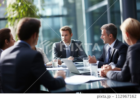 A group of business people are sitting around a table having a meeting A group of business people are sitting around a table having a meeting 112967162