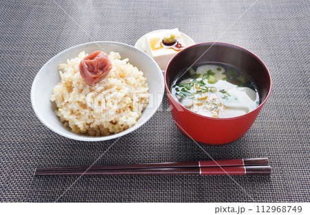 漬物が乗った炊き立ての玄米ごはんと熱々のお味噌汁と豆腐の和食の朝食 112968749