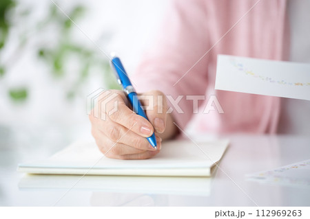 手紙を書くミドル女性の手元 112969263