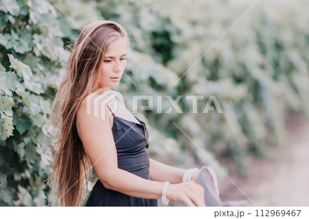 Woman travel winery. Portrait of happy woman holding glass of wine and enjoying in vineyard. Elegant young lady in hat toasting with wineglass smiling cheerfully enjoying her stay at vineyard. Woman travel winery. Portrait of happy woman holding glass of wine and enjoying in vineyard. Elegant young lady in hat toasting with wineglass smiling cheerfully enjoying her stay at vineyard. 112969467