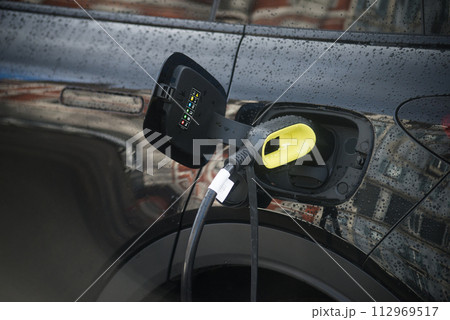 Closeup of black electric car charging at the station in the street 112969517