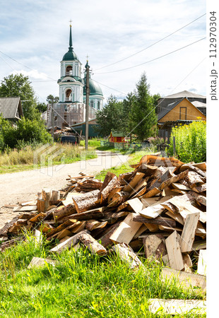 Chopped dry firewood at the countryside against a church Chopped dry firewood at the countryside against a church 112970304