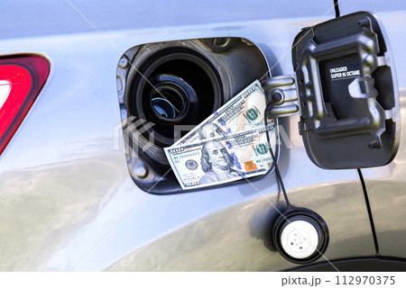 American dollars bills in the gas tank of a vehicle. Concept photo of the rising fuel price 112970375
