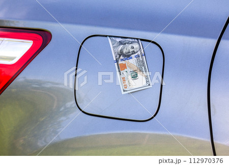 American dollars bills in the gas tank of a vehicle. Concept photo of the rising fuel price 112970376