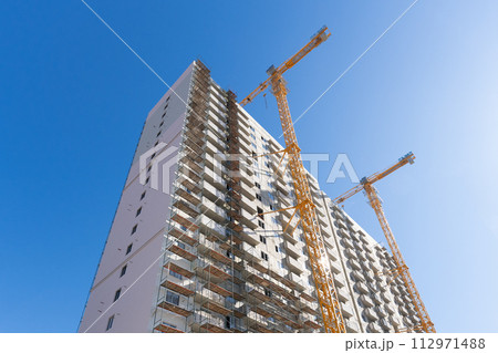 Construction of a multi-storey building using a high-rise yellow crane. Home construction. 112971488