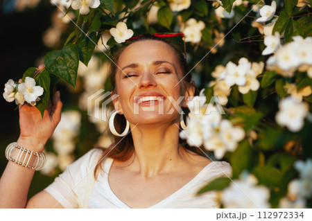 happy young woman in white shirt near flowering tree happy young woman in white shirt near flowering tree 112972334