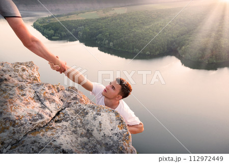 Man help his friend to climb on the rock Man help his friend to climb on the rock 112972449