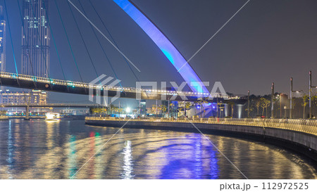 Futuristic Pedestrian Bridge over the Dubai Water Canal Illuminated at Night timelapse, UAE. Futuristic Pedestrian Bridge over the Dubai Water Canal Illuminated at Night timelapse, UAE. 112972525