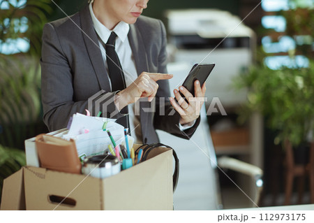 unhappy woman employee in green office using smartphone unhappy woman employee in green office using smartphone 112973175