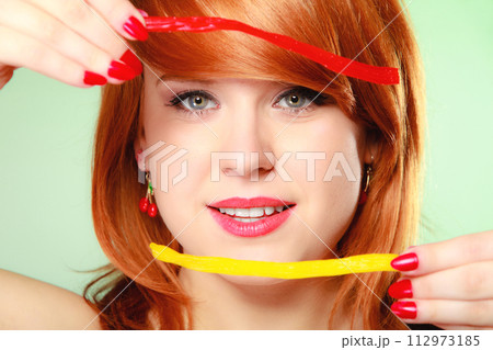 Redhair girl holding sweet food jelly candy on green. Redhair girl holding sweet food jelly candy on green. 112973185