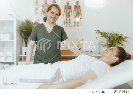 smiling therapist woman in massage cabinet doing checkup 112973451