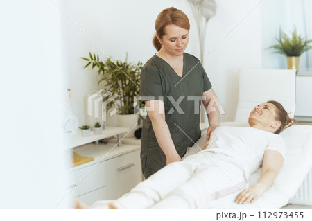 female therapist in massage cabinet doing checkup 112973455