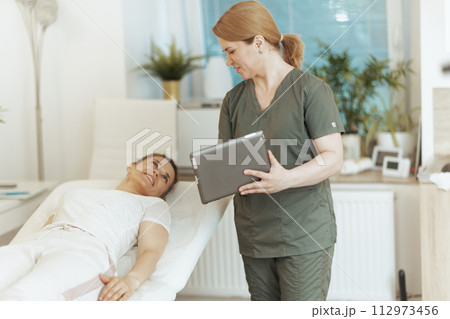 smiling female massage therapist in massage cabinet with client smiling female massage therapist in massage cabinet with client 112973456