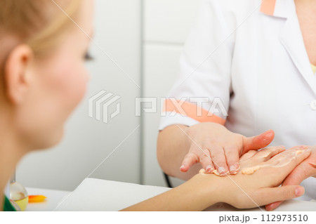 Woman applying cream on hand using spatula 112973510