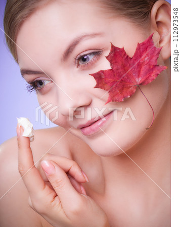 Skin care. Face of young woman girl with red maple leaf. Skin care. Face of young woman girl with red maple leaf. 112973548