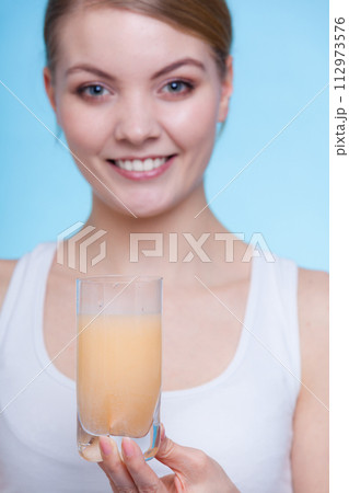 Woman holding glass with water and effervescent tablet Woman holding glass with water and effervescent tablet 112973576