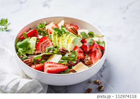 Strawberry and avocado salad with arugula, parmesan, nuts and lemon zest. 112974118