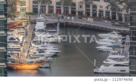 Promenade and canal in Dubai Marina with luxury skyscrapers and yachts around timelapse, United Arab Emirates Promenade and canal in Dubai Marina with luxury skyscrapers and yachts around timelapse, United Arab Emirates 112974698