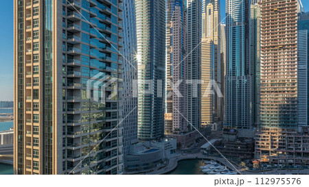 View of modern skyscrapers shining in sunset lights timelapse in Dubai Marina in Dubai, UAE. View of modern skyscrapers shining in sunset lights timelapse in Dubai Marina in Dubai, UAE. 112975576